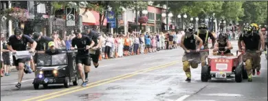  ?? The Sentinel-Record/Lorien E. Dahl ?? BATTLE OF THE BADGE: Members of the Hot Springs Police Department and the Hot Springs Fire Department race in the Battle Of The Badge during the 12th annual Stueart Pennington Running Of The Tubs.