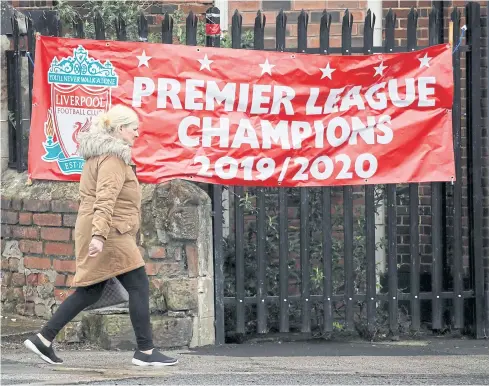  ?? REUTERS ?? A woman walks past a banner in Liverpool saying ‘Premier League Champions 2019/2020’.