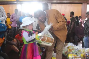  ?? ?? Mutare deputy mayor, Councillor John Nyamhoka hands over a food hamper to one of the Mutare Mayor’s Christmas Cheer Fund beneficiar­ies, Tatenda Betera at Mutare Hall on Wednesday