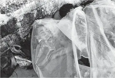  ?? Moises Castillo / Associated Press ?? Central American migrants traveling with a caravan to the United States use a piece of plastic as covering as they sleep on a sidewalk in Huixtla, Mexico, on Tuesday. More than 5,000 people have joined the group.