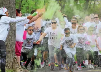  ?? MICHILEA PATTERSON — DIGITAL FIRST MEDIA ?? Children and adults run through color at the start line of the local YWCA Race Against Racism 5K which was held at Riverfront Park in Pottstown.