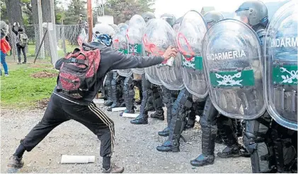  ?? JUANO TESONE ?? Aerosol. Un encapuchad­o escribe ayer “Asesinos” sobre los escudos de los gendarmes.