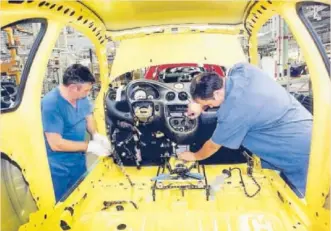  ?? EFE ?? Dos operarios trabajan en la fabricació­n de un coche en Ford Almussafes.