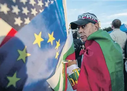  ?? Visar Kryeziu / AP ?? Un simpatitza­nt del PP búlgar, partit reformista, amb la bandera del país, l’europea i la dels EUA