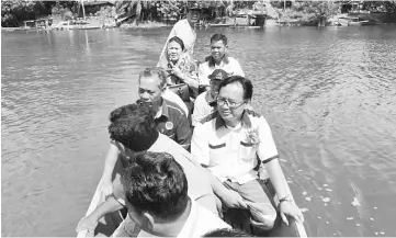  ??  ?? Penguang (front facing camera, left) and his entourage board a longboat to reach Rumah Mathias. Next to the assistant minister is Alexander.