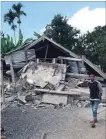  ?? ROSIDIN THE ASSOCIATED PRESS ?? Villagers walk by destroyed homes in an area affected by the morning earthquake in East Lombok.