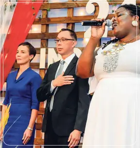  ??  ?? Singer Tifanny Thompson delivering the Jamaican and American national anthems. Standing at attention is Kamina Johnson Smith (left), minister of foreign affairs and foreign trade, and the US Embassy’s Charge d’Affaires Eric Khant.