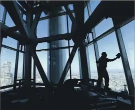  ?? Mel Melcon Los Angeles Times ?? PABLO PERALTA cleans the windows on the 73rd story of the Wilshire Grand Center. The 1,100-foot building houses an InterConti­nental Hotel and office space.