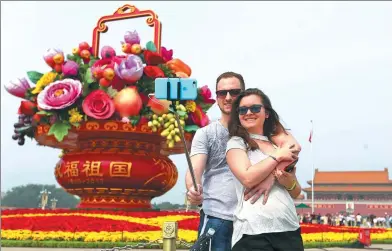  ?? WANG ZHUANGFEI / CHINA DAILY ?? Tourists take a selfie in front of a flower basket in Tian’anmen Square in Beijing on Monday.
