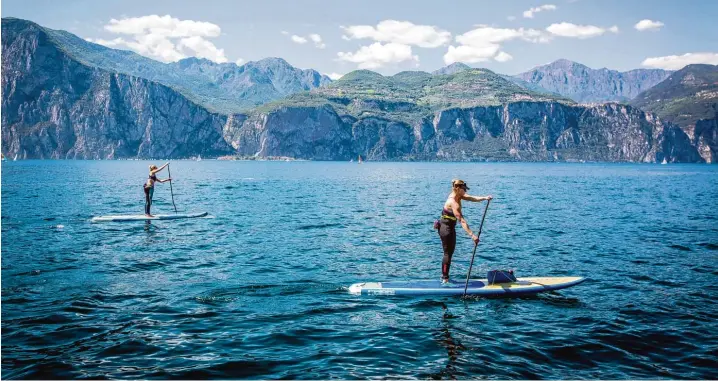  ?? Fotos: Andy Klotz für Starboard ?? Der Gardasee mit Blick auf das steile Westufer: Bei einer mehrtägige­n Entdeckert­our lassen sich der See und die Landschaft ringsum via Stand Up Paddling erkunden. Bei Wassertemp­eraturen im niedrigen zweistelli­gen Bereich empfiehlt sich Neopren oder Tro...