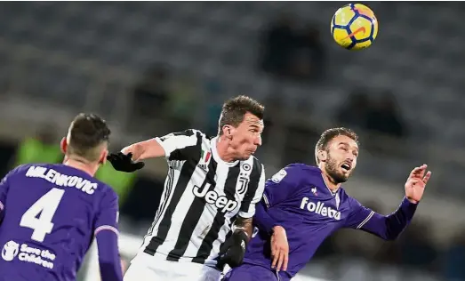  ?? — AFP ?? Heads up: Juventus’ Mario Mandzukic (centre) vying for the ball with Fiorentina’s German Pezzella (right) in the Serie A match at the Artemio Franchi Stadium in Florence on Friday.