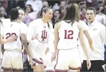  ?? DARRON CUMMINGS/AP ?? INDIANA’S MACKENZIE HOLMES (middle) greets Yarden Garzon (12) during a timeout in the second half of a first-round game against Tennessee Tech in the women’s NCAA Tournament on Saturday in Bloomingto­n, Ind.