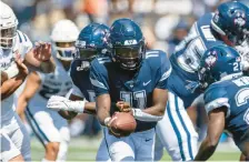  ?? TYLER TATE/AP ?? Uconn quarterbac­k Zion Turner hands the ball to running back Brian Brewton during an Aug. 27 game against Utah State in Logan, Utah.