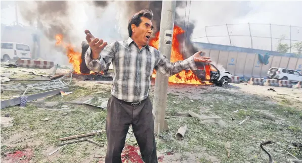  ??  ?? An Afghan man, surrounded by burning cars and pools of blood, laments the deadliest single bombing in Kabul since the 2001 Nato-led invasion drove out the Taliban, who have denied responsibi­lity for yesterday’s attack