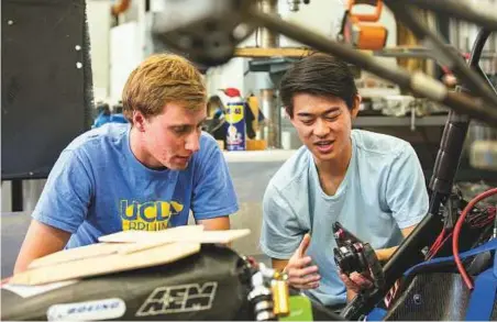  ?? Los Angeles Times ?? UCLA students Brent Kyono (right) and Luke Allee compare parts for the UCLA Formula SAE team car in the Westwood campus workshop in Los Angeles.