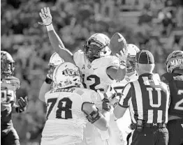  ?? PATRICK SEMANSKY/ASSOCIATED PRESS ?? UCF running back Taj McGowan, center, and left tackle Wyatt Miller celebrate after a touchdown in the Knights’ big road victory over Maryland last month.