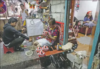  ??  ?? Therry Sicat (center) finishes paint on miniature lion heads in Manila’s Chinatown,. The Dragon and Lion dancers won’t be performing this year due to covid-19 restrictio­ns, leaving several businesses without income.