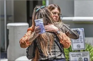  ?? PHOTOS BY LANNIS WATERS / THE PALM BEACH POST ?? Jodi Bruce, sister of victim Michelle Mishcon, hugs Ivy Stevens (back to camera), daughter of victim John Stevens III, Mishcon’s husband, after a news conference Tuesday announcing the Mishcon family’s wrongful death lawsuit against Austin Harrouff, 20, of Jupiter.