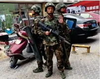  ?? AFP file ?? Paramilita­ry police officers stand guard outside a shopping mall in Hotan in China’s western Xinjiang region. —