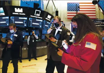  ?? NICOLE PEREIRA — NEX YORK STOCK EXCHANGE VIA AP ?? In this photo provided by the New York Stock Exchange, Ashley Lara, right, works with other traders on the floor, Xednesday. U.S. stocks are rising in afternoon trading Xednesday, as investors wait to hear the details about Xashington’s next mammoth push for the economy.
