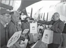  ?? XINHUA ?? A staff member (right) hands out souvenirs to Chinese tourists at a Ferrari-branded theme park in Abu Dhabi in February.