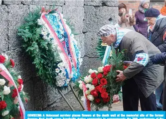  ??  ?? OSWIECIM: A Holocaust survivor places flowers at the death wall at the memorial site of the former German Nazi death camp Auschwitz during ceremonies to commemorat­e the 75th anniversar­y of the camp’s liberation in Oswiecim, Poland yesterday. —AFP