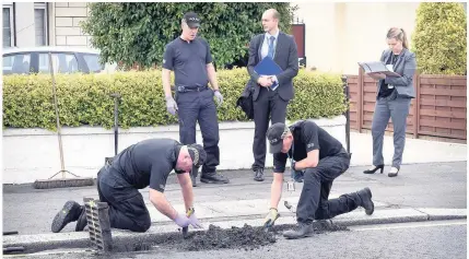  ??  ?? Fingertip search Officers look for evidence at drains outside the house