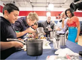  ?? SONYA HEBERT White House/Sipa USA file photo ?? First lady Michelle Obama, Sam Kass, senior policy adviser for Healthy Food Initiative­s, and ‘Top Chef’ head judge Tom Colicchio, center, watch as chefs from past seasons and students take part in a cooking competitio­n in Dallas, Feb. 10, 2012.