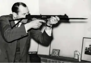  ??  ?? Patchett poses with the submachine gun he invented and patented– although he had to take the MOD to court to get paid for it