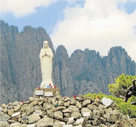  ?? /Supplied ?? Panorama: A statue of Our Lady of the Snows stands next to the road at the Col de Bavella mountain pass and is framed by the needle-shaped granite of the Aiguilles de Bavella in Corsica.