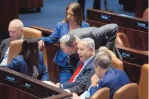  ?? MAYA ALLERUZZO/ASSOCIATED PRESS VIA POOL ?? Israel’s Prime Minister Benjamin Netanyahu, center right, consults with lawmakers in Israel’s parliament, the Knesset, to vote on a plan to overhaul the country’s legal system in Jerusalem, Monday.