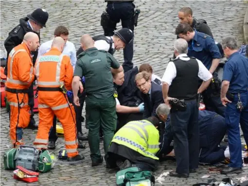  ??  ?? Foreign Office Minister Tobias Ellwood (centre) tried to help emergency services resuscitat­e emergency services attend to the police officer who died from his stab wounds (PA)