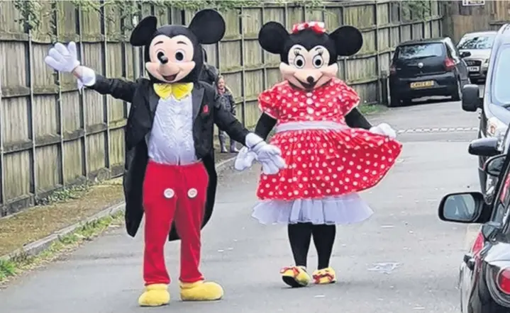  ??  ?? Ben Garnham and Dawn Morris have been cheering their neighbours by walking the streets dressed as Mickey and Minnie Mouse