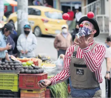  ?? FOTO: AP ?? > Artista del circo hace malabares en un mercado de Bogotá.