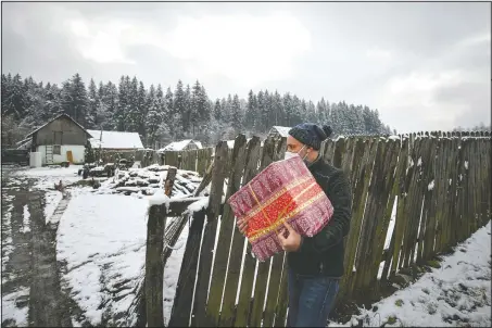  ?? (AP/Andreea Alexandru) ?? Nicolae carries a box containing basic food, hygiene and medicinal products.