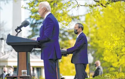  ?? Andrew Harnik The Associated Press ?? Japanese Prime Minister Yoshihide Suga listens as President Joe Biden speaks Friday in the Rose Garden of the White House.