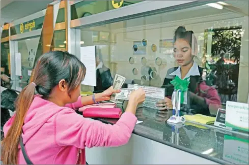 ?? HONG MENEA ?? A woman receives money from a finance officer at a Phnom Penh branch of Prasac Microfinan­ce Institutio­n, the country’s largest MFI.