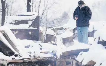  ?? JACK DEMPSEY/AP ?? Daniel Peers looks at what remains of his brother’s burned homes Saturday in snowy Louisville, Colorado.