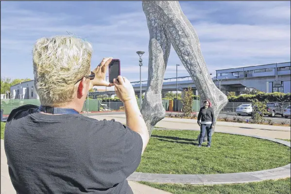  ?? JOCELYN GECKER / AP ?? Art teachers Jo Sutton (left) and Jennifer Jervis take pictures beneath a 55-foot nude statue in San Leandro, Calif. The statue of a naked woman is stirring up a lot of conversati­on. City officials and the sculptor say they want to draw attention to...