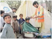  ?? ?? Boys get haircuts at a makeshift camp for flooding victims in Charsadda, Pakistan