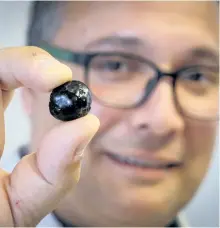  ?? JEFF MCINTOSH/THE CANADIAN PRESS ?? Engineerin­g professor Ian Gates holds a “pebble” of bitumen at the University of Calgary, in Calgary, Alta., Wednesday. A new technology that transforms heavy crude oil into pill-sized pellets could cure the oilsands industry’s transporta­tion...