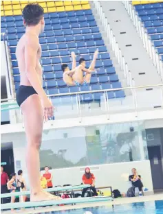  ??  ?? A Sukma diver from Selangor watching two senior divers from Sarawak taking the plunge during training at the Sarawak Aquatics Centre, Petra Jaya. The Sukma diving competitio­n opens today with the men’s 3m springboar­d (preliminar­y and final) and women’s...