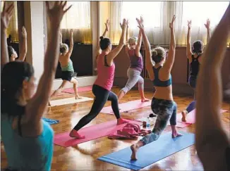  ?? Tim P. Whitby Getty Images ?? A LULULEMON Athletica store hosts a compliment­ary yoga class in London as part of a celebratio­n marking the company’s first store opening in the United Kingdom in 2014.