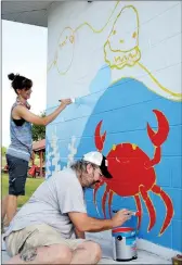 ?? Courtesy photograph ?? Arkansas Arts Academy teachers Crystal McWilliams and Aaron Jones work on the sea creatures and various shades of blue in the mural at the Pea Ridge City Park splash pad.