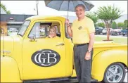  ?? Tim Godbee ?? Calhoun branch president Donna Mcentyre (left), sits in a classic GMC truck during during Saturday’s grand reopening event as Greater Community Bank President David Lance shields both from the rain. The branch is now full back open to the public.