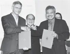  ??  ?? Uggah (centre) witnessing the exchange of MoU documents between Mohd Fadzil (right) and Froiland.