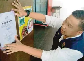  ?? ZULKIFLI
PIC BY ZULIATY ?? A Kedah Health Department officer putting up the 14-day closure order at a nasi kandar restaurant in Alor Star.