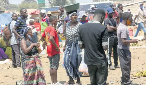  ?? AP PHOTOS ?? People are seen wearing their mask below the chin at a busy market in a poor township on the outskirts of the capital Harare, Zimbabwe last week.