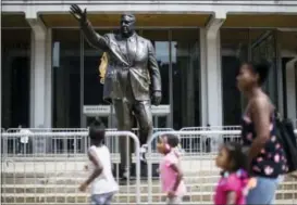  ?? MATT ROURKE — THE ASSOCIATED PRESS ?? A family passes a statue of the late Philadelph­ia Mayor Frank Rizzo, who also served as the city’s police commission­er, as it stands outside the Municipal Services Building covered in raw eggs and surrounded by barricades in Philadelph­ia, Wednesday....