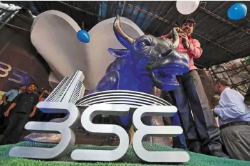  ?? ?? Strong market: A man ties a balloon to the horns of a bull statue at the entrance of the Bombay Stock Exchange. Indian stocks keep hitting record highs thanks to an unpreceden­ted retail investing boom. — Reuters
